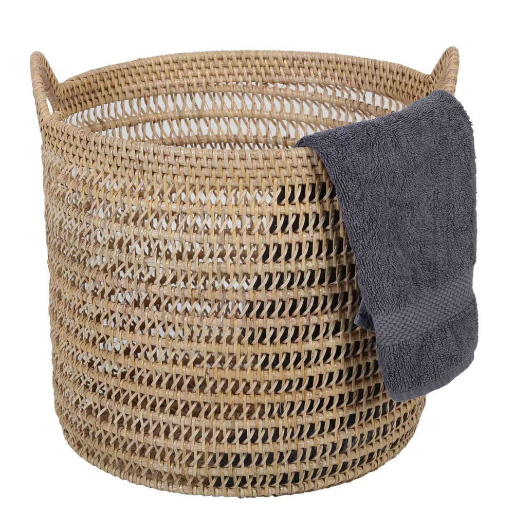 Cesto Eda in rattan color naturale a intreccio aperto, con due manici e asciugamano grigio scuro sul bordo.