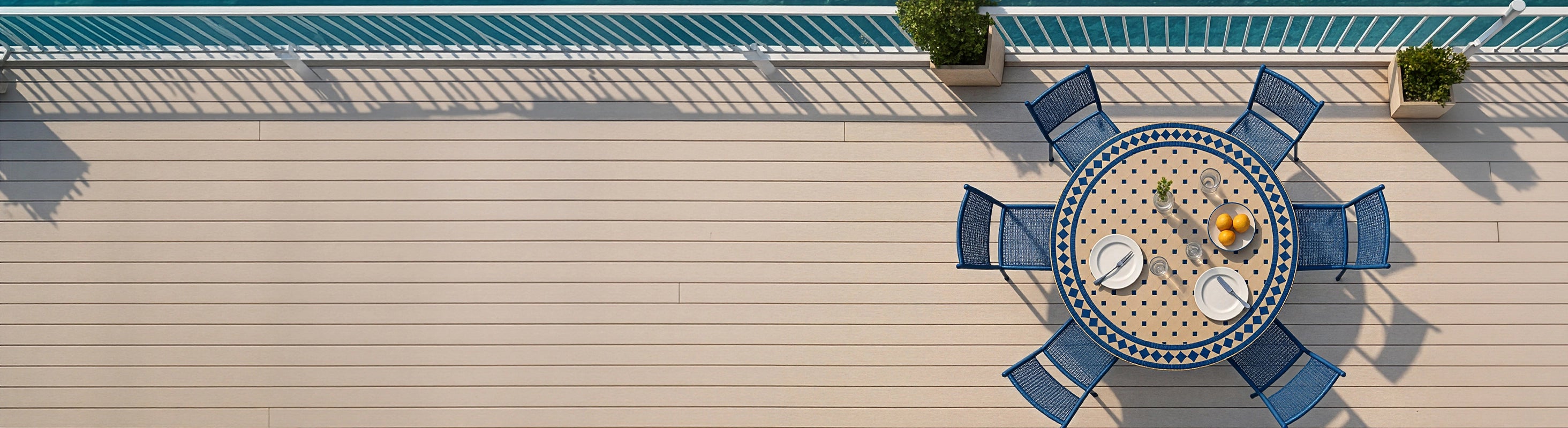 Tavoli in mosaico Ø120 – Grande tavolo rotondo in mosaico Ø120 cm con piastrelle zellige blu e diverse sedie viste dall'alto sulla terrazza con vista mare