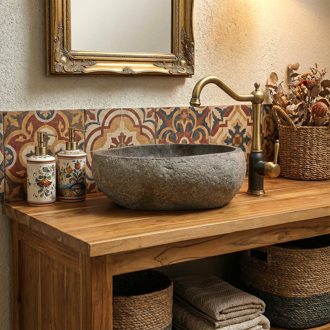 Natursteinwaschbecken in warmem Boho-Badezimmer auf Holzwaschtisch, kombiniert mit Messingarmatur und gemusterten Fliesen