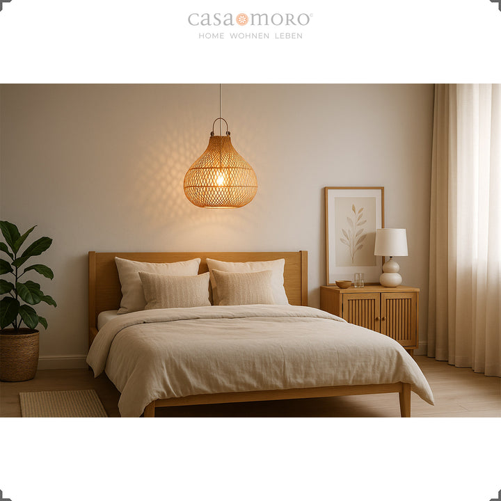 Natürliche Rattanlampe über Bett im Schlafzimmer mit warmem Licht und heller Einrichtung