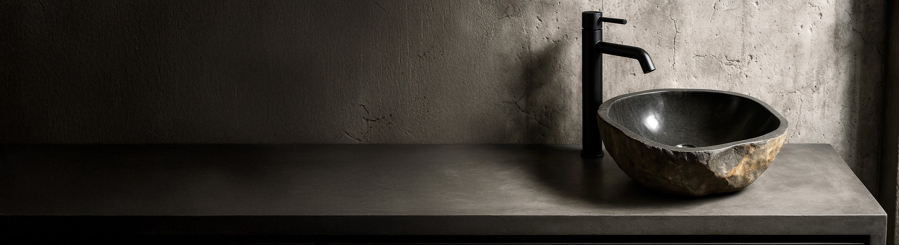 Lavabo in pietra – Bagno moderno con lavabo in pietra naturale realizzato in marmo, legno fossile e pietra di fiume su una semplice consolle in cemento.