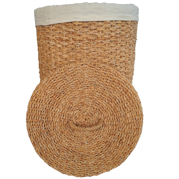 Cesto portabiancheria in alghe marine di colore naturale con inserto in tessuto chiaro e coperchio posizionato davanti.
